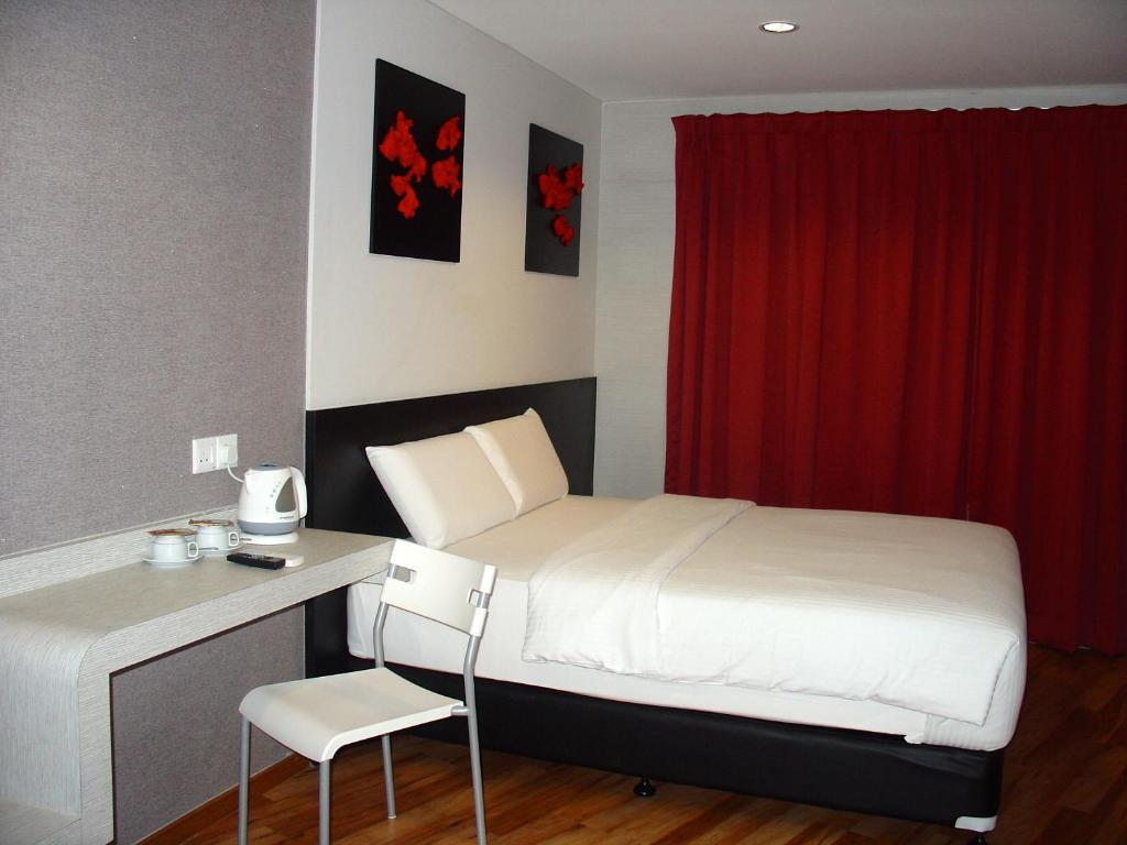 a bedroom with a bed with a desk and a red curtain at Alor Boutique Hotel Sdn Bhd in Kuala Lumpur
