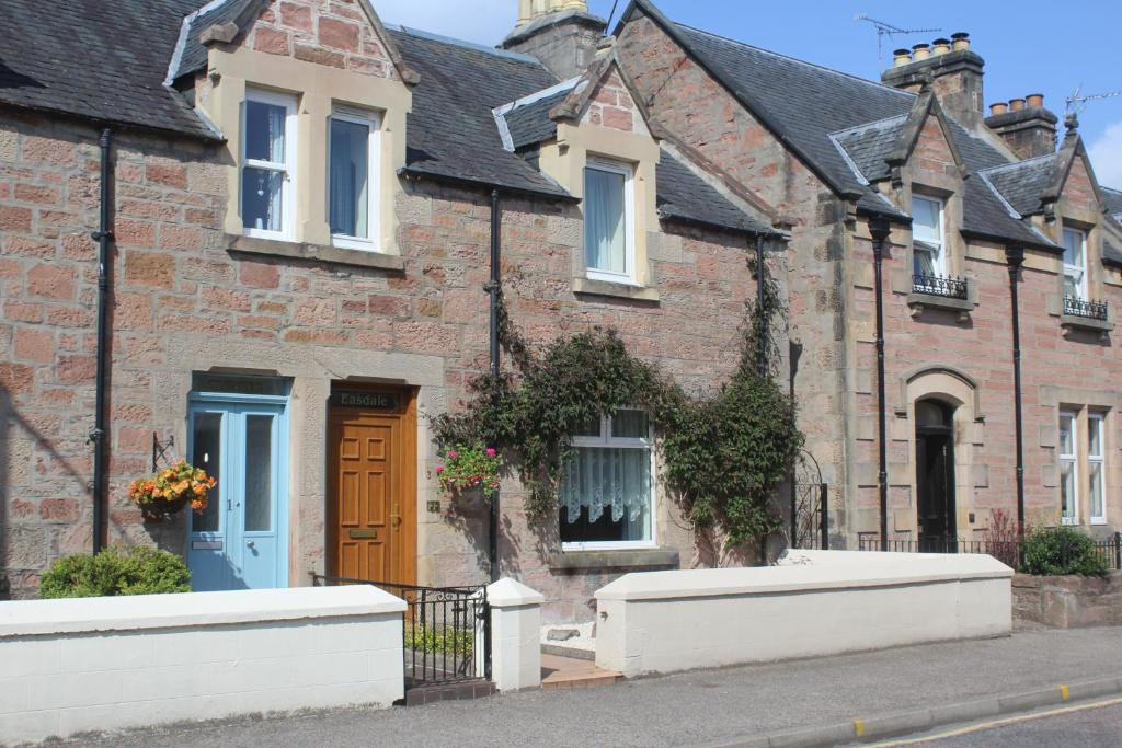 a brick house with a blue door on a street at Easdale House Apartments in Inverness