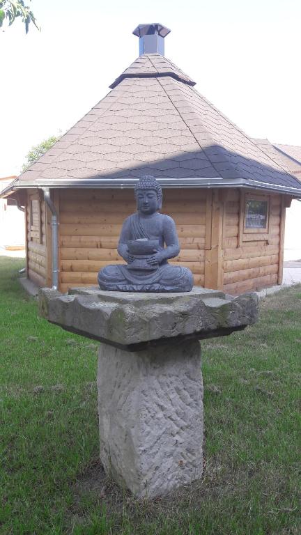 una statua seduta sopra una struttura in pietra di Ferienwohnung Gänseblümchen a Wartenburg