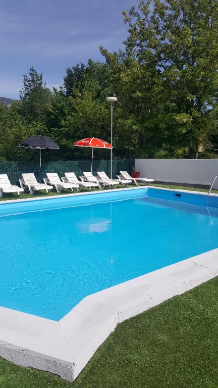 a large blue swimming pool with chairs and an umbrella at Camping Le Pesquier in Castellane