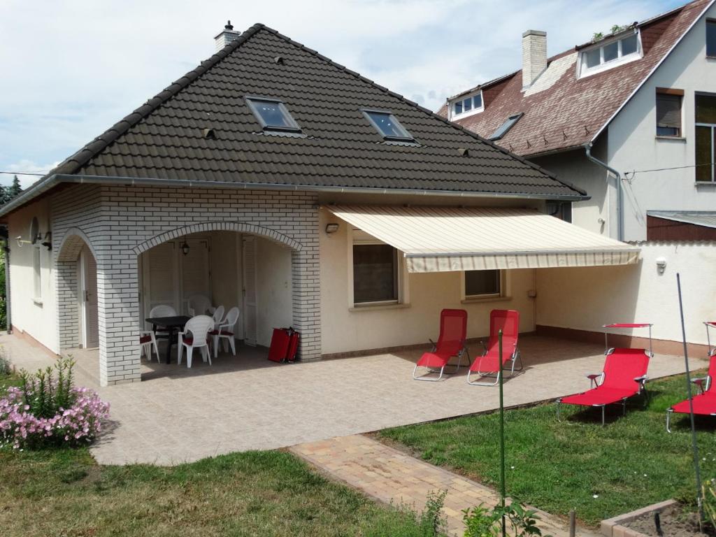 een huis met een patio met rode stoelen en een tafel bij House Magnolia in Velence