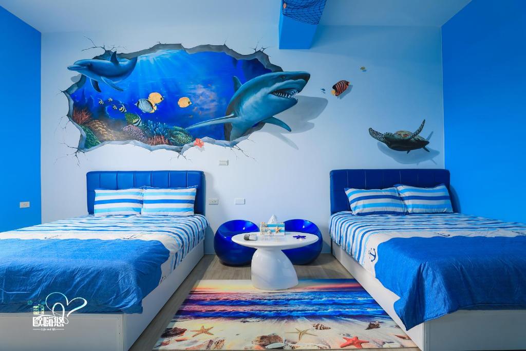 馬公市的住宿－歐嗨悠民宿，一间带两张床和鱼壁画的卧室