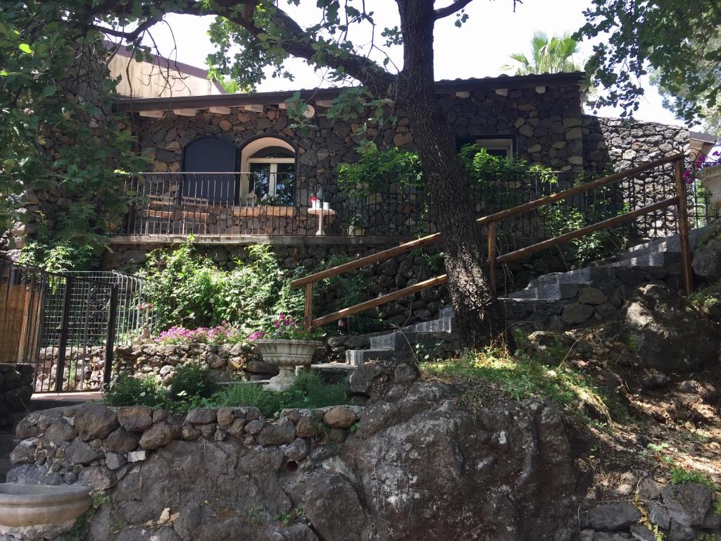 a stone house with a tree and a fence at Aprisa apartment in Piedimonte Etneo