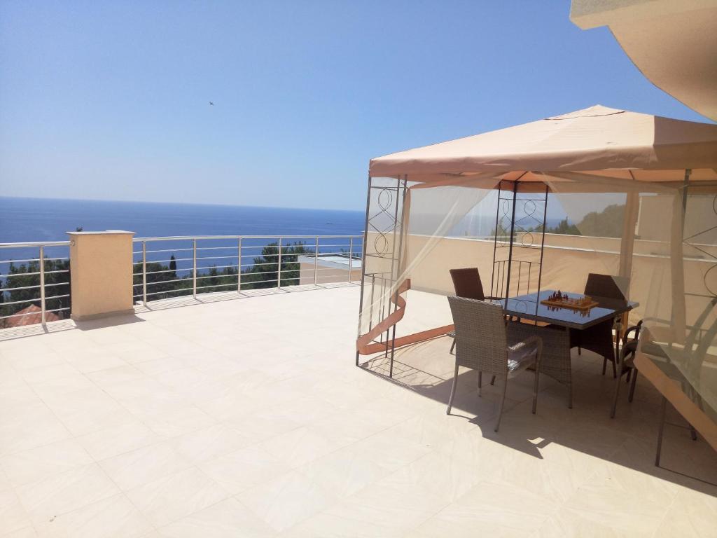 une table et des chaises sur un balcon avec l'océan dans l'établissement Villa Roan, à Bar