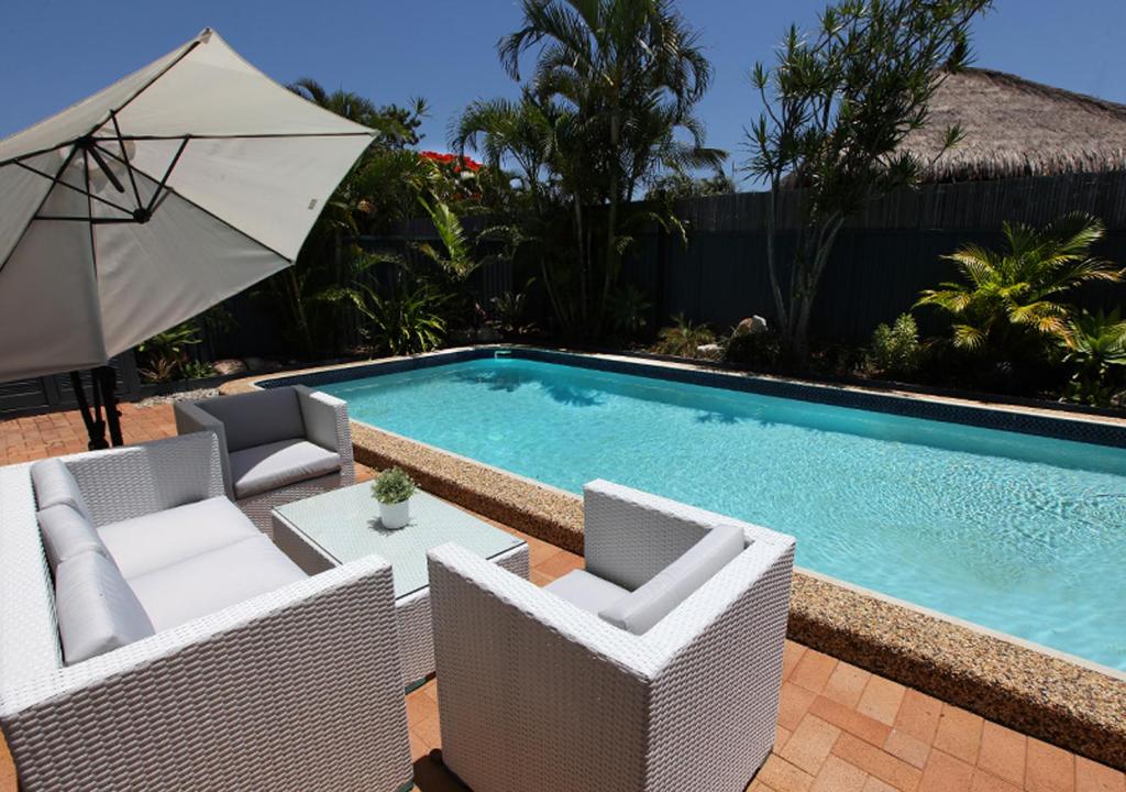 a swimming pool with two chairs and an umbrella at Mermaid Beach House in Gold Coast