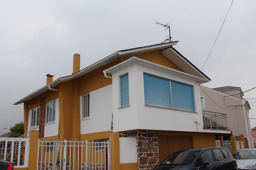 a yellow and white house with blue shutters at Casa do Roxo de Rinlo Nº REGISTRO VUT-LU-00706 in Rinlo