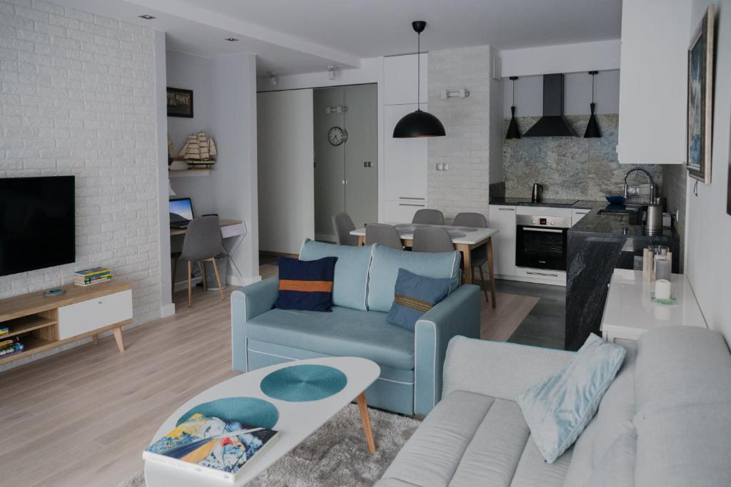 a living room with a blue couch and a kitchen at ASKI New Powiśle Copernicus Apartment in Warsaw
