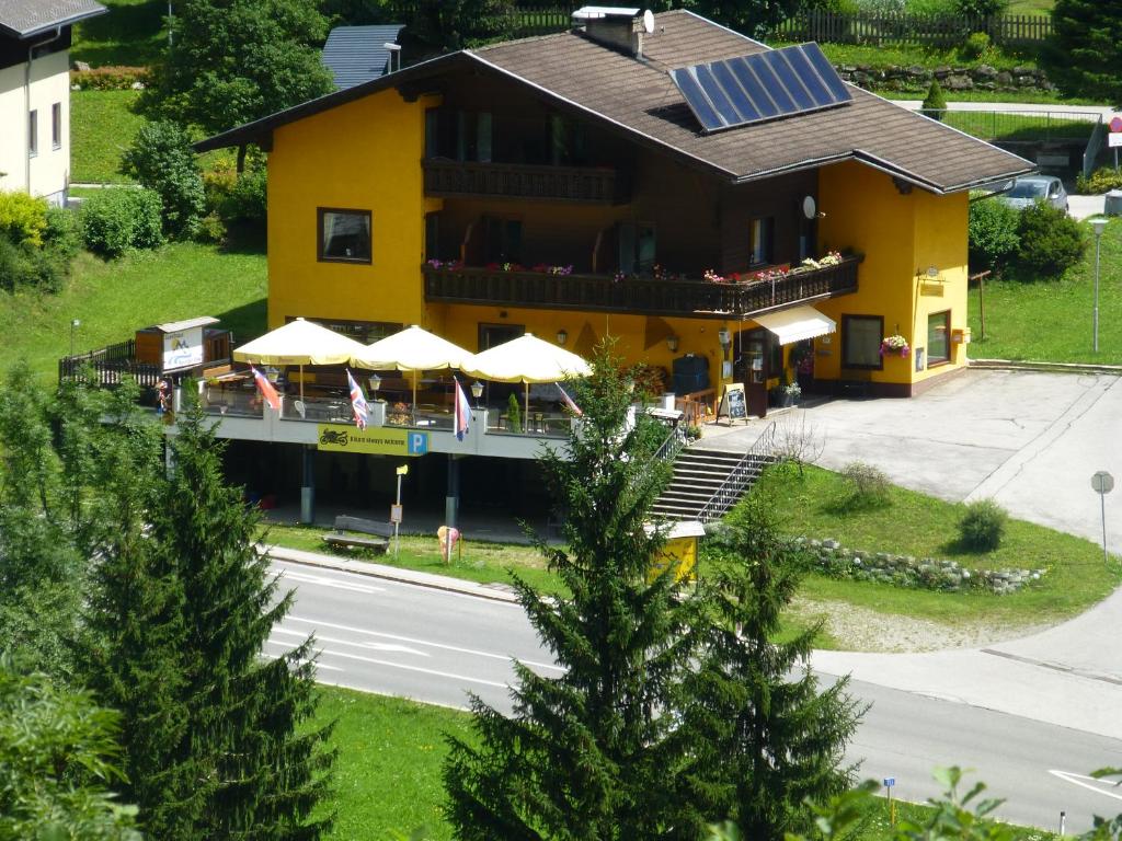 un edificio amarillo con un restaurante con sombrillas en Guesthouse Mountain View en Großkirchheim
