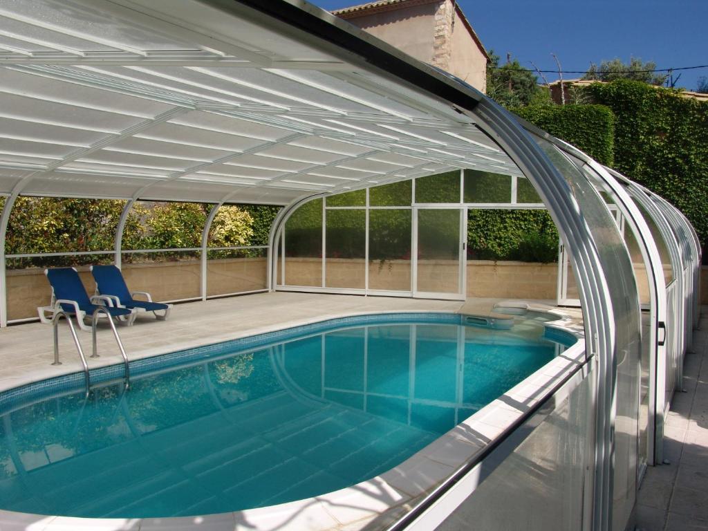 an expandable pergola over a swimming pool with a patio at Apartamentos Casa Sanz in Asque