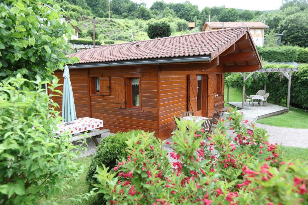 a small wooden cabin with a bench and an umbrella at Chalet de Grettery in Saulxures-sur-Moselotte