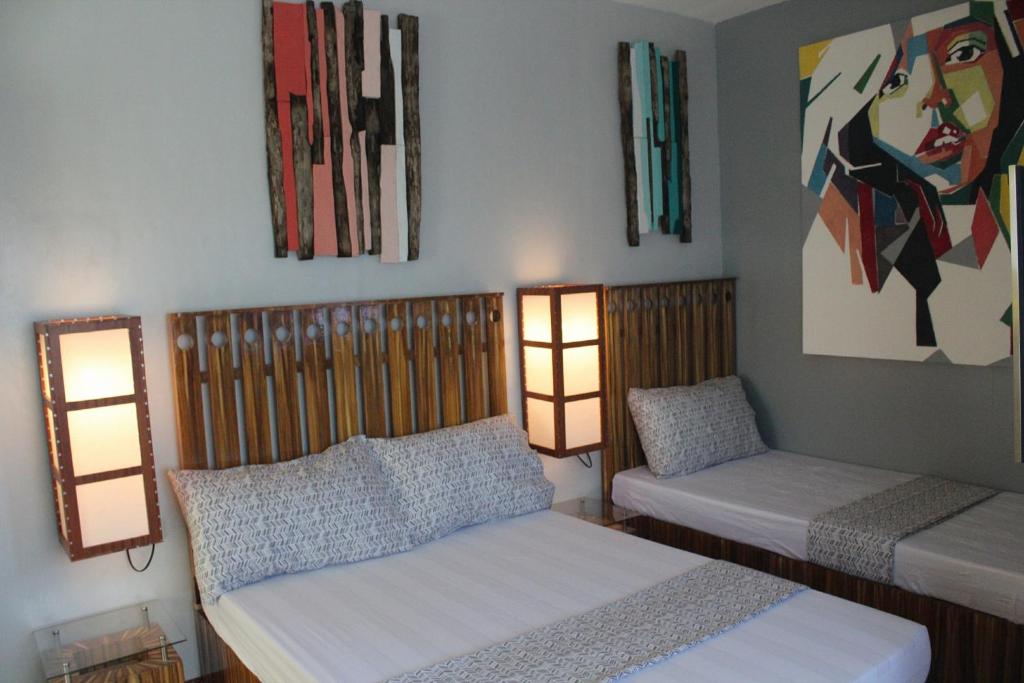 a bedroom with two beds and two lights on the wall at Gomez Guest House in Tagbilaran City