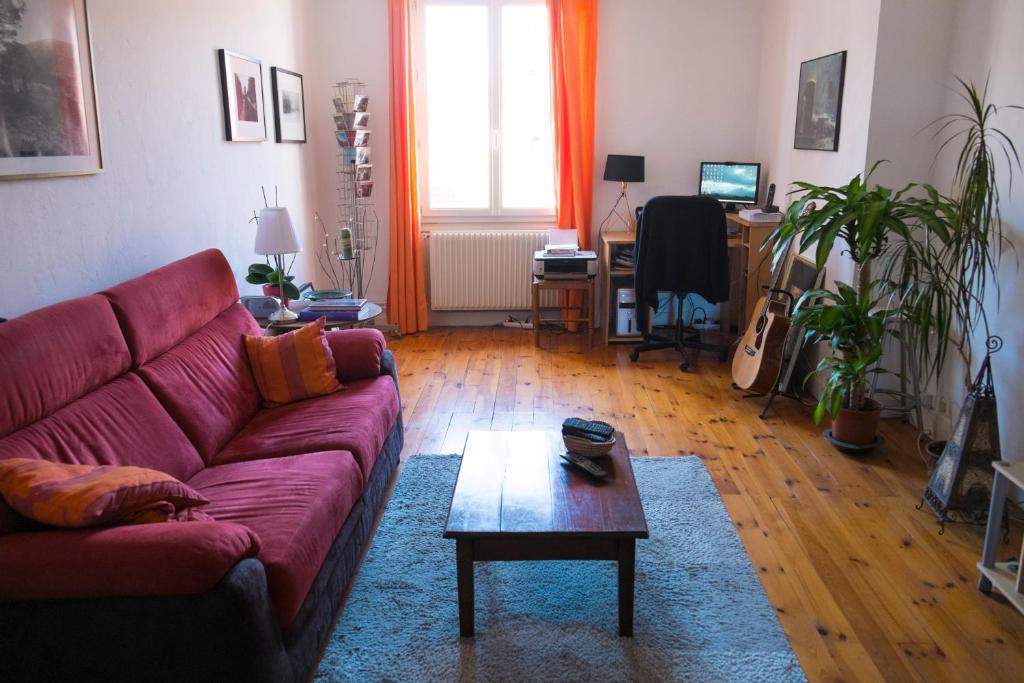 a living room with a red couch and a table at Appartement centre ville Le Puy in Le Puy en Velay