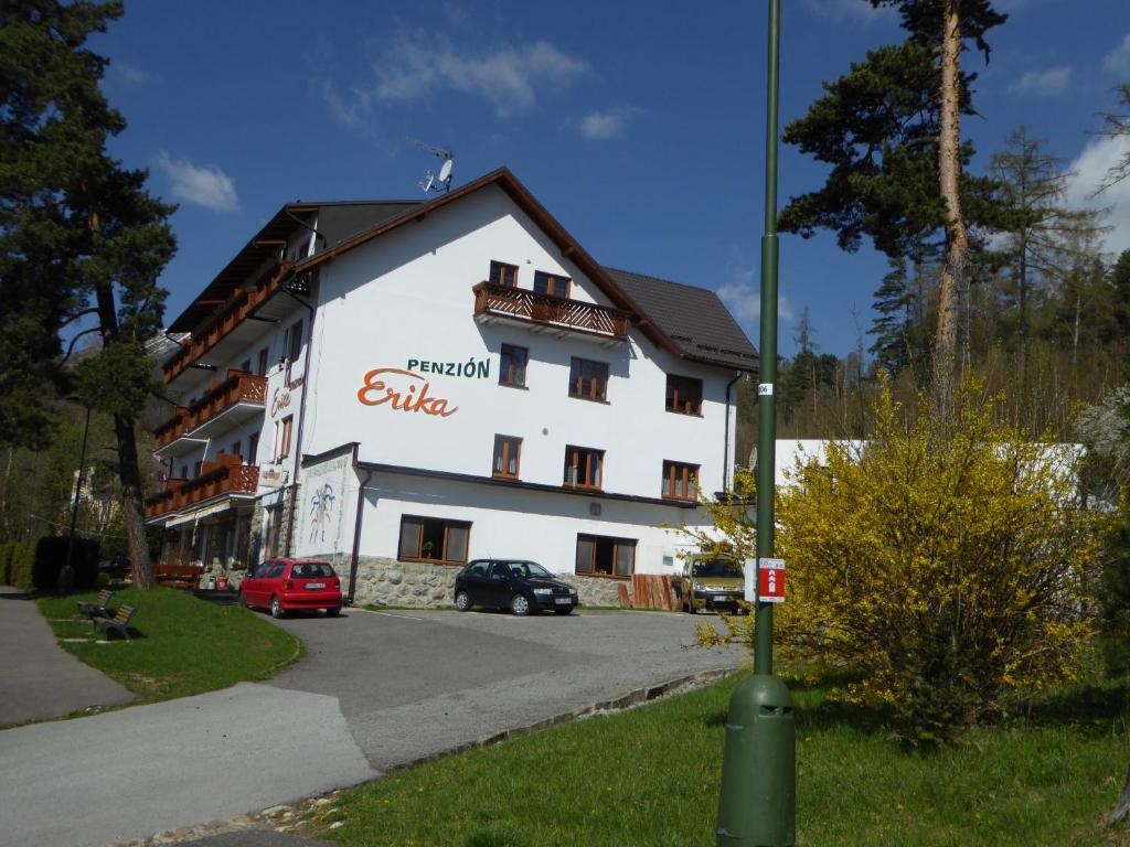 ein weißes Gebäude mit einem Schild an der Seite in der Unterkunft Erika penzión in Vysoke Tatry - Tatranska Lesna