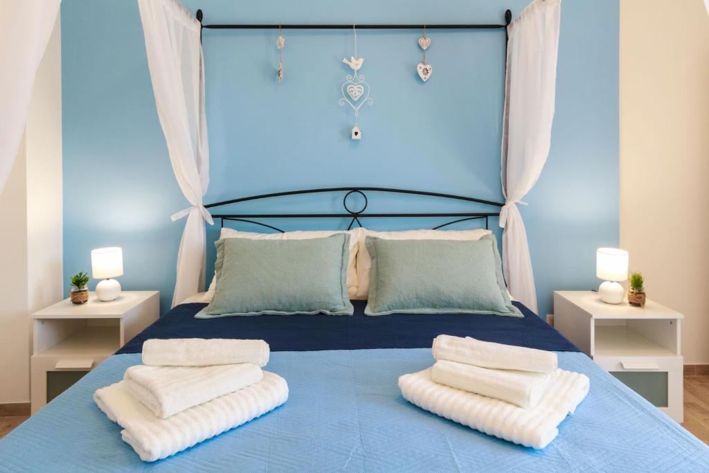 a bedroom with a blue bed with towels on it at Lumia e Zagara in Taormina