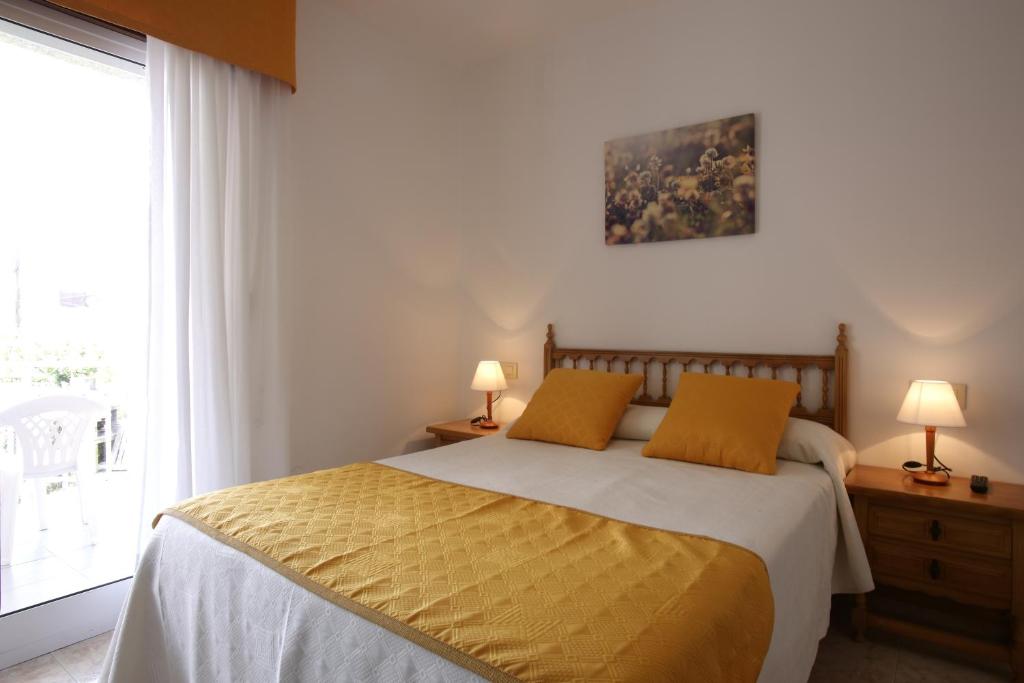 a bedroom with a bed with two lamps and a window at Hostal San Roque in Portonovo