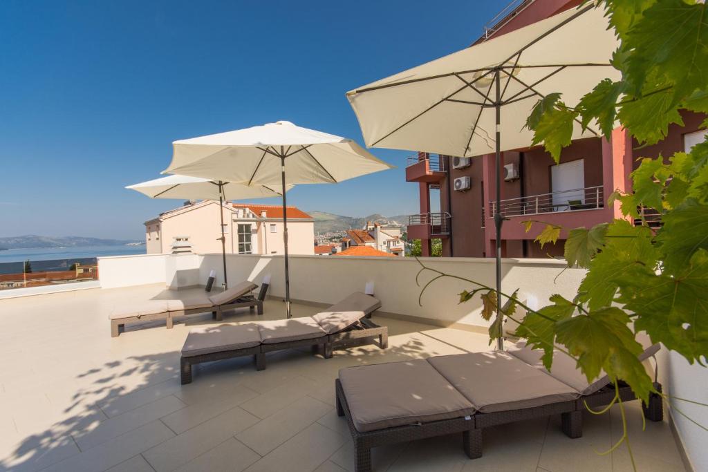 eine Terrasse mit Bänken und Sonnenschirmen auf dem Dach in der Unterkunft Apartmani- Lastro in Trogir