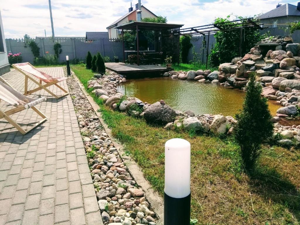 a pond in a yard with sheep in the grass at Rakovskii in Rakov