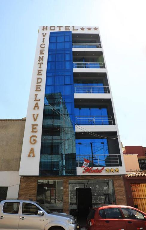 Un edificio alto con coches aparcados delante. en Hotel Vicente de la Vega, en Chiclayo