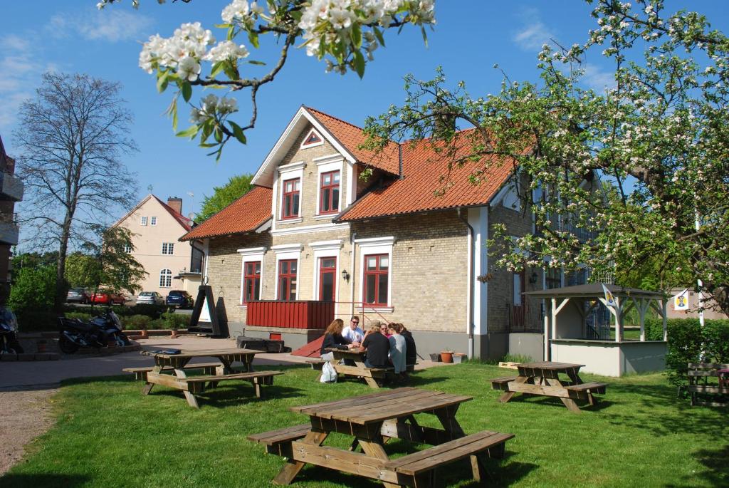 grupa ludzi siedzących przy stołach piknikowych przed domem w obiekcie Åhus B&B och Vandrarhem w mieście Åhus