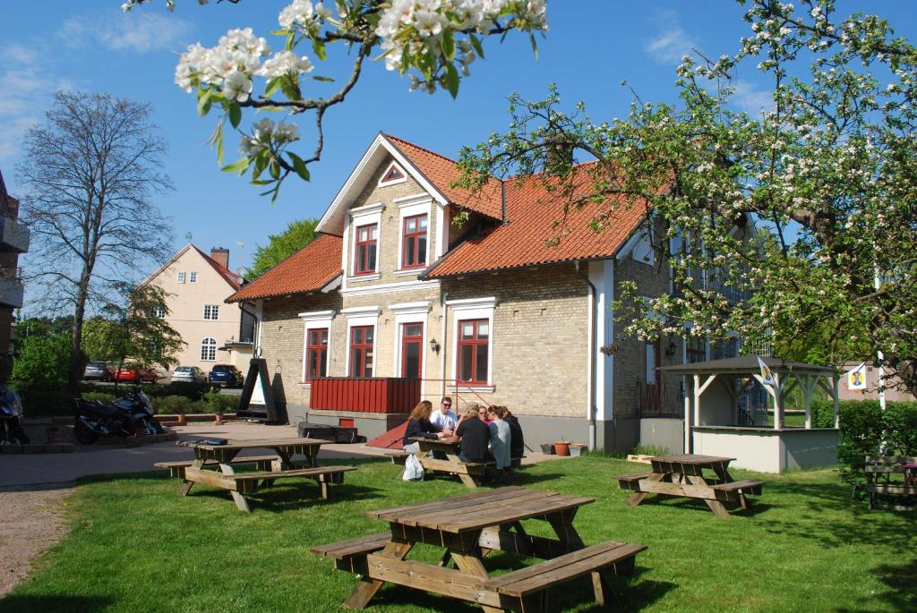 a group of people sitting at picnic tables in front of a house at Åhus B&B och Vandrarhem in Åhus