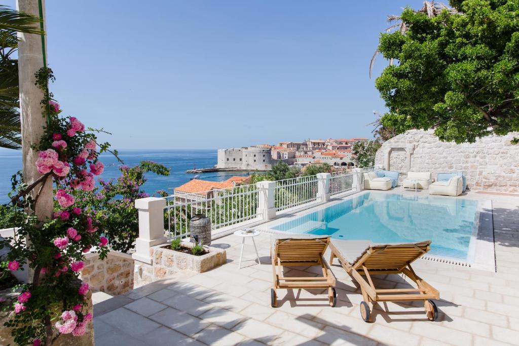 a swimming pool with two chairs and a view of the ocean at Villa Beba Dubrovnik - luxury boutique villa in the city centre in Dubrovnik