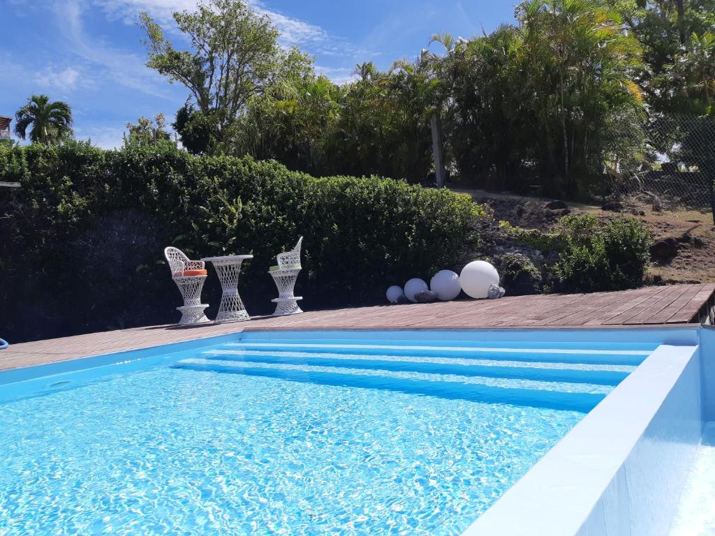 a swimming pool with blue water and white eggs on the side at Domaine Choco Vanille in Deshaies