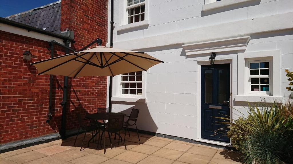 um pátio com uma mesa e um guarda-chuva ao lado de um edifício em Island View em Lymington