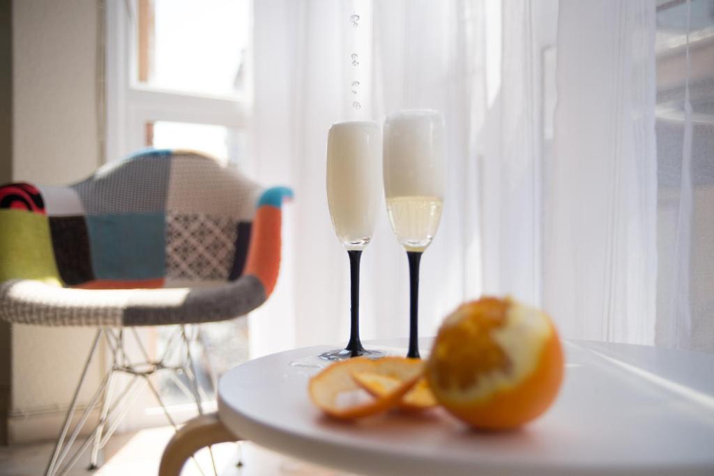 two wine glasses and an orange on a table at Apartment Grand Fernando Explanada Alicante in Alicante