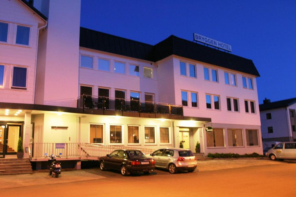 努德福來德的住宿－Nordfjord Hotell - Bryggen，两辆汽车晚上停在大楼前