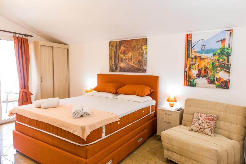 a bedroom with a large bed and a chair at Apartments & Studios Tomanović in Budva