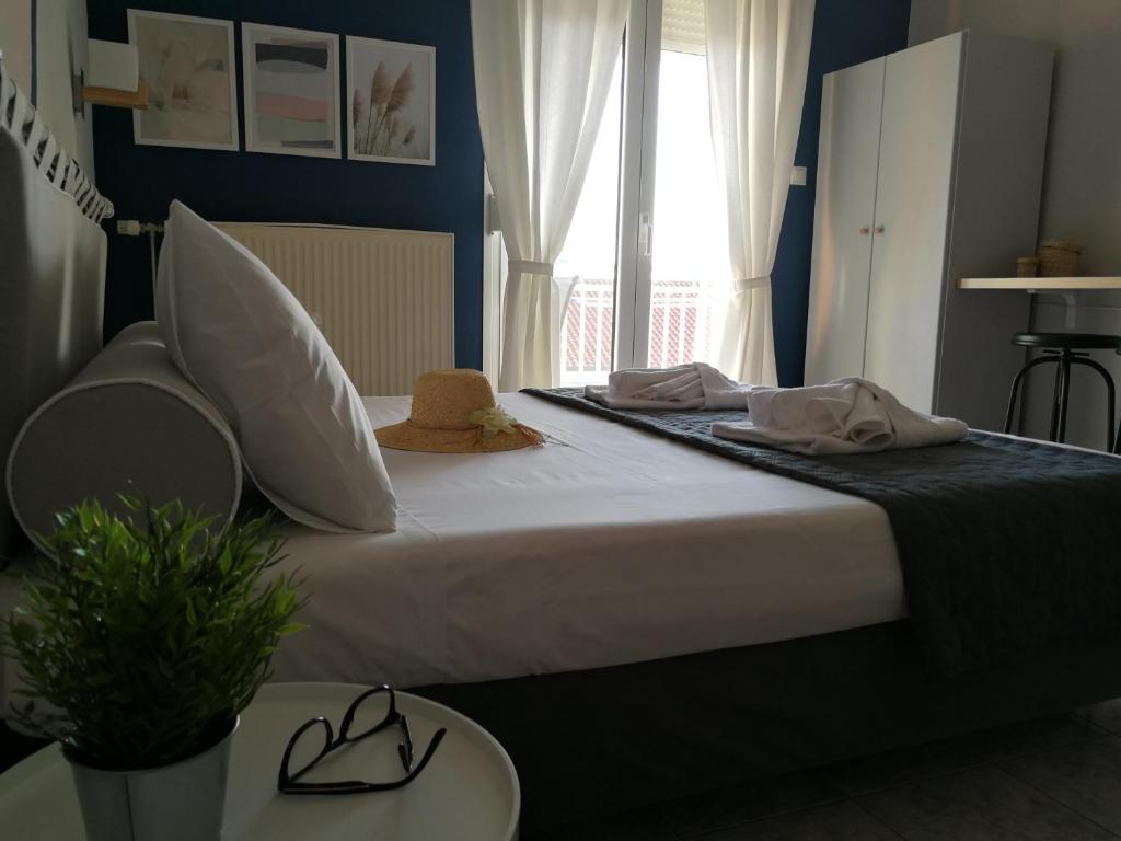 Un dormitorio con una cama con sombreros y una ventana en PhiloxenInn en Polýgyros