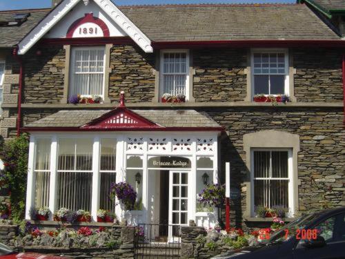Casa de piedra con una puerta delantera blanca y ventanas en Briscoe Lodge, en Windermere