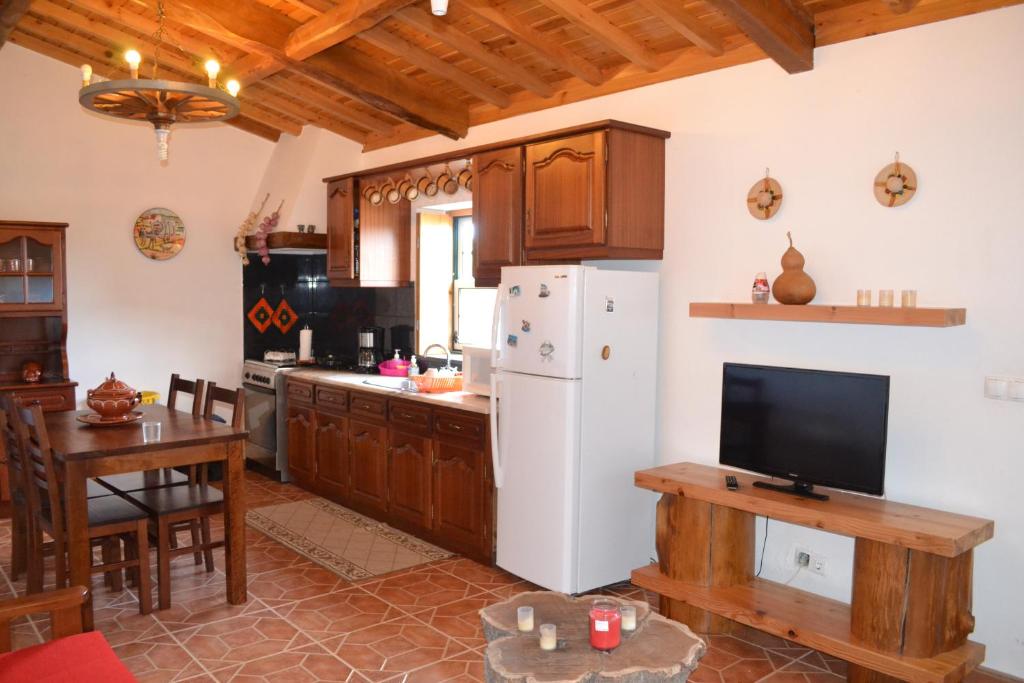 eine Küche mit einem weißen Kühlschrank und einem Tisch in der Unterkunft Adega Mendes in Porto Martins