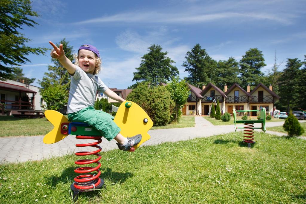 a little girl riding on top of a toy in the grass at OW Diana in Łazy