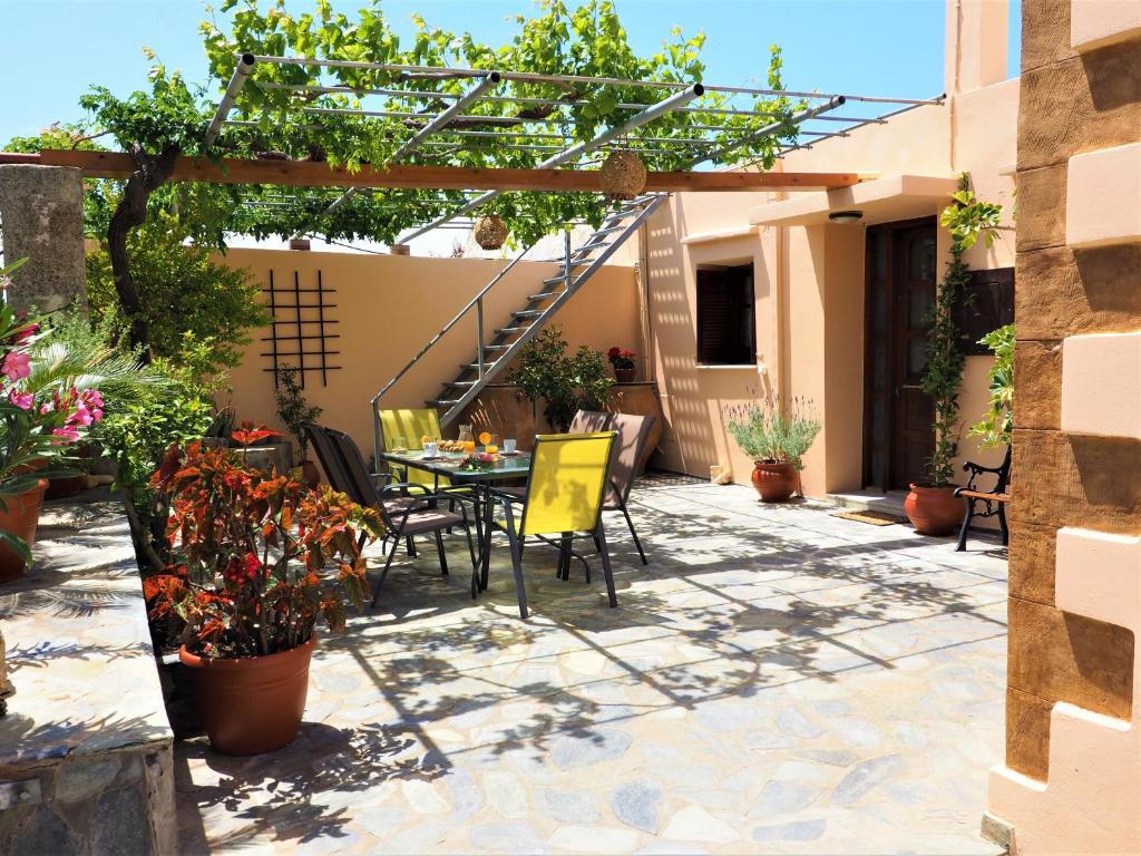 un patio con mesa, sillas y plantas en Traditional Cretan Villa, en Rodhopós