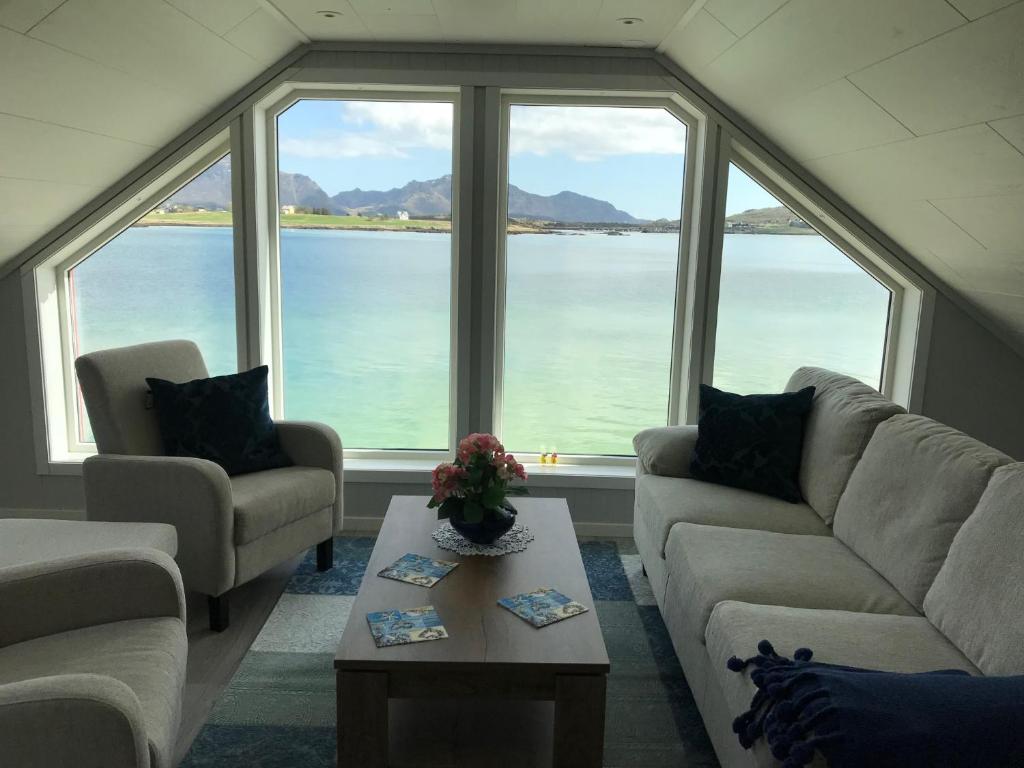 una sala de estar con sofás y vistas al agua. en Luxurious cabin by the waterfront, en Leknes
