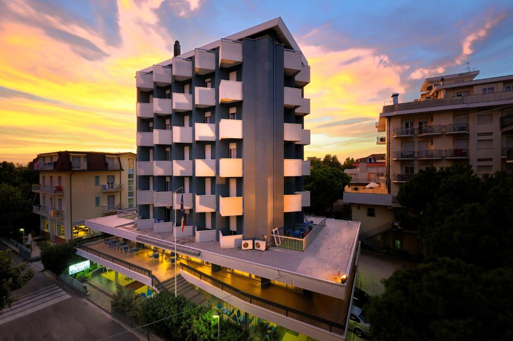 un edificio de hotel con una puesta de sol en el fondo en Hotel Raffaello, en Bellaria-Igea Marina