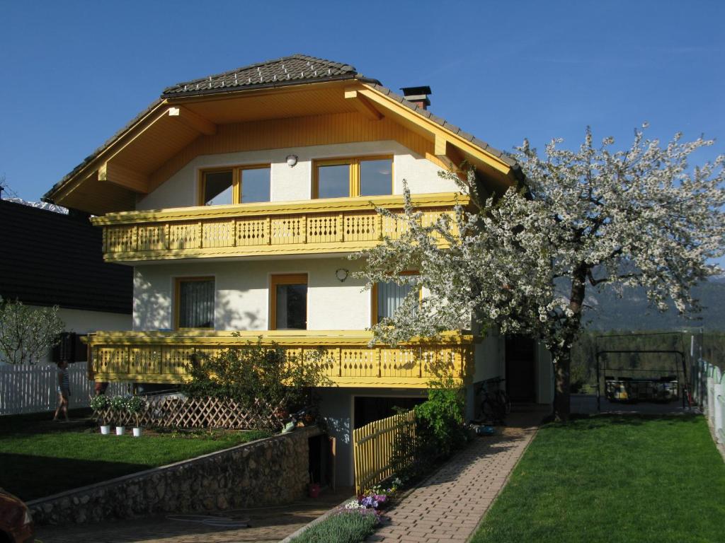 a yellow house with a balcony and a tree at Apartma AS in Bled