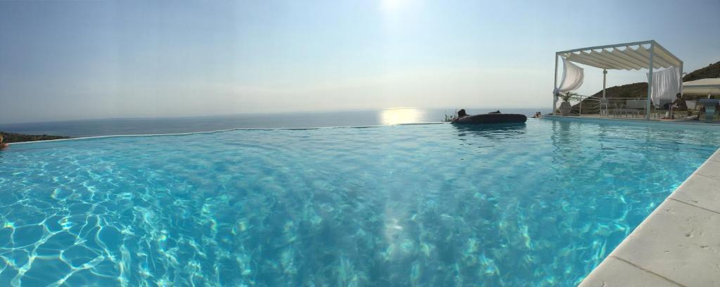 een groot blauw zwembad met de oceaan op de achtergrond bij White Club Residence in Belvedere Marittimo