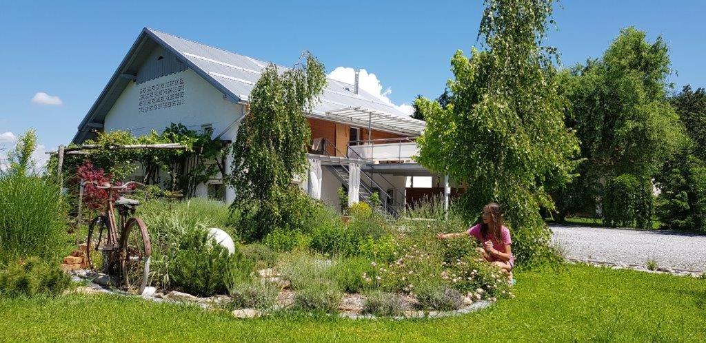 una mujer sentada en un jardín frente a una casa en Hillside Bio Resort Delux Apartments, en Šešče pri Preboldu