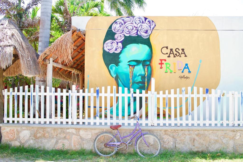 Una bicicleta púrpura estacionada junto a una valla con un mural en CASA FRIDA FULL APARTMENTS holbox, en Isla Holbox
