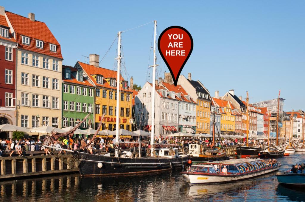 a group of boats docked in a river with buildings at Colourful Nyhavn Experience in Copenhagen