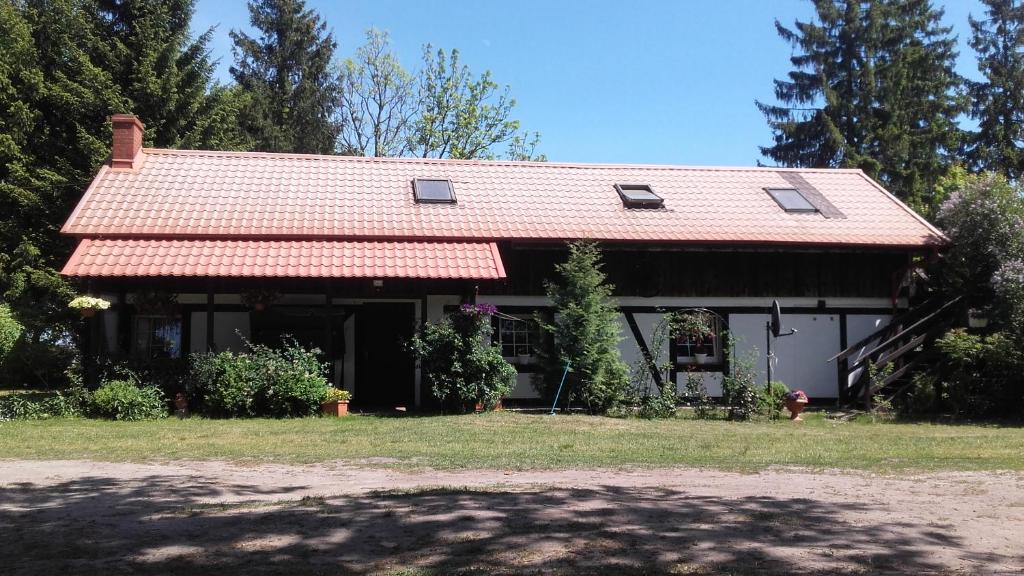una casa con techo rojo y patio en Agroturystyka Pod Dębami w Klukach en Smołdzino