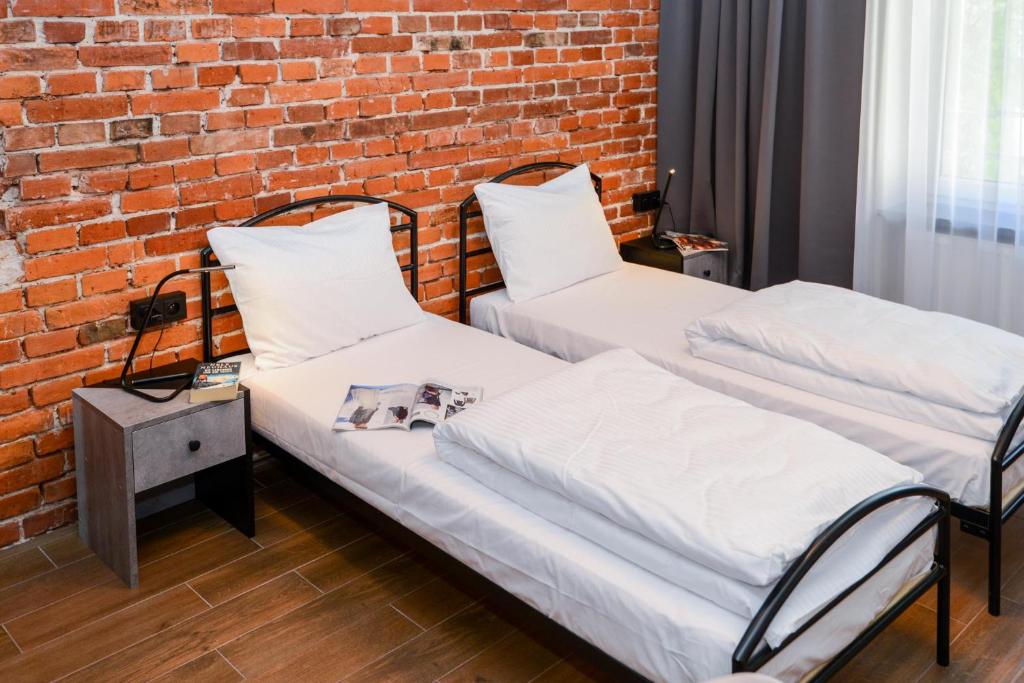 two beds in a room with a brick wall at Cracow Apartaments III in Krakow