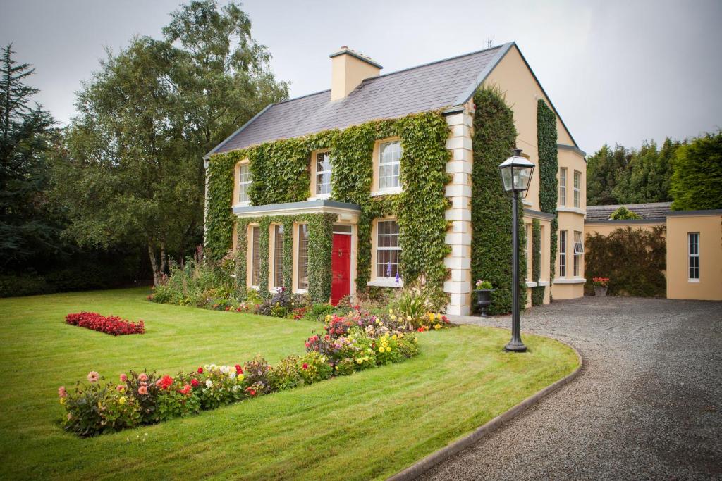 una casa con una puerta roja y flores en el patio en Friars Quarter House B&B, en Ballinrobe