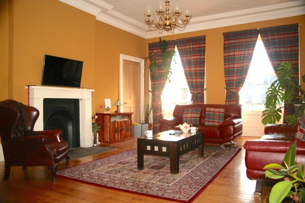 a living room with chairs and a table and a fireplace at Hopetoun Grande Georgian Apartment in Edinburgh