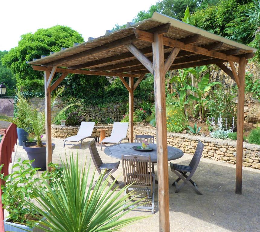 a wooden pavilion with a table and chairs at Charmante Maison Troglodyte in Vitrac