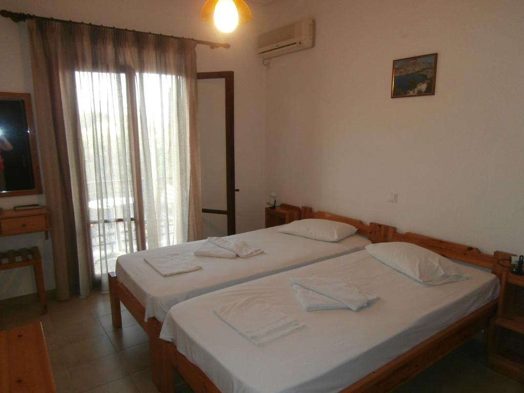 sypialnia z 2 łóżkami i dużym oknem w obiekcie Hotel Aris w mieście Methoni