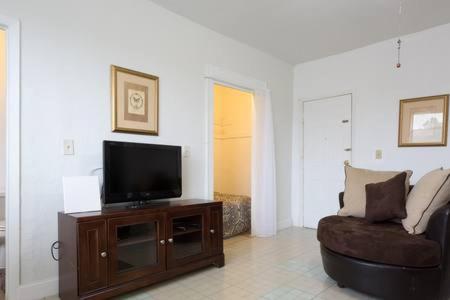 uma sala de estar com uma televisão e um sofá em Gallo Condo 33/downtown/8st em Miami