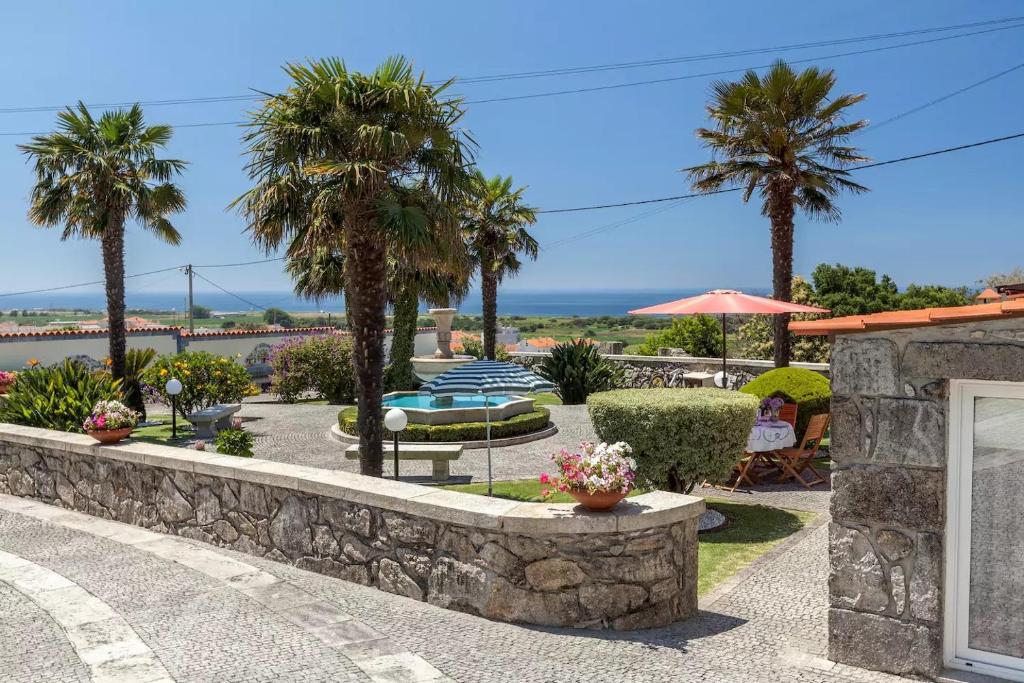a resort with palm trees and a stone wall at Casa do Chafariz in Viana do Castelo